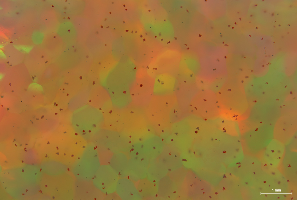 Figure 2 : (a) L'opale contient des inclusions de cinabre rouge sur toute la sub-surface du cabochon. 