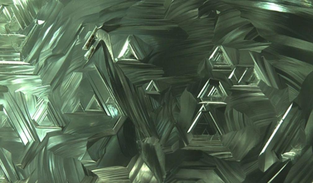 Trigons on the surface of a green diamond crystal.